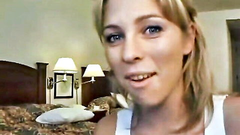 Blonde teen babe smiling with deep cleavage in tight white tank top on hotel bed