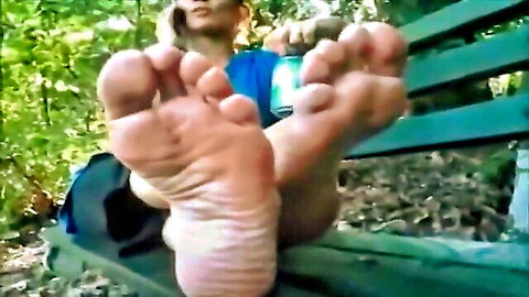 Sexy Asian girl in blue top showing bare foot soles on bench outdoors