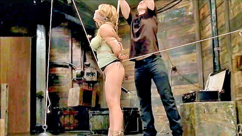 Blonde curvy MILF with huge tits bound in tight rope bondage by man in BDSM dungeon