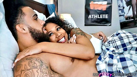 Muscular tattooed black guy cuddles smiling curvy ebony babe in bed