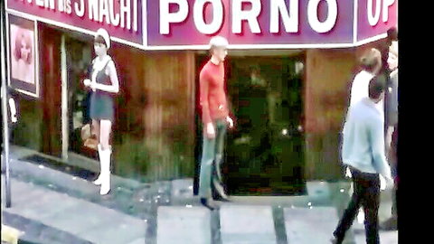 Vintage street scene of sexy mini-skirted woman in go-go boots outside Nackt Porno shop with men.