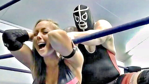 Blonde woman in bikini dominated by masked Titan in wrestling ring action