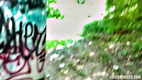 Blurry outdoor Czech streets scene with graffiti and greenery