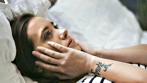 Seductive brunette with tattooed hand caressing her perky tits on bed