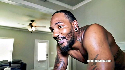 Muscular black man with tattoos smiling shirtless in adult video