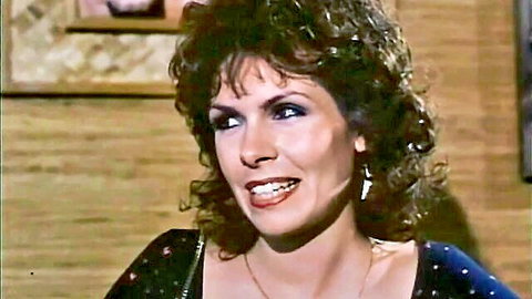 Vintage porn star Annette Haven smiling seductively in low-cut dress