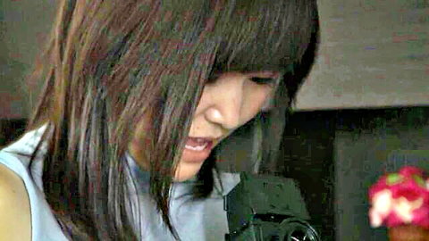 Asian woman with long brown bangs in light blue top at microphone