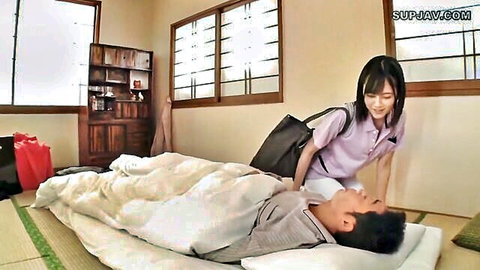 Clothed Japanese woman in purple polo leans over smiling man lying on futon bed