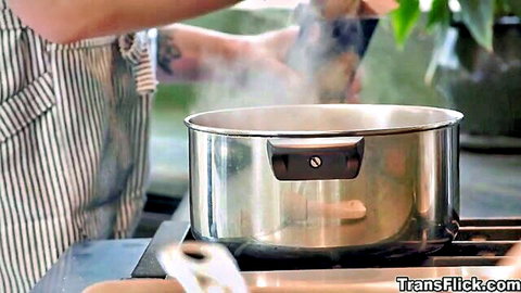 Chef in striped apron stirring steaming pot on stove with wooden spoon
