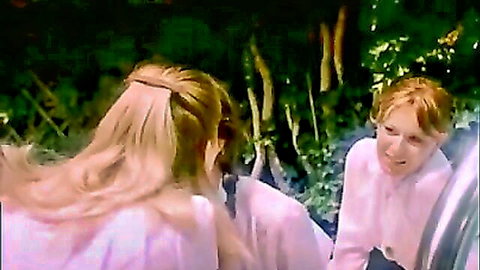Blonde ponytail girl and smiling redhead in pink tops chatting outdoors in garden amateur video
