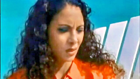 Curly-haired Latina woman in orange shirt with intense expression, Passion Cove The Gift