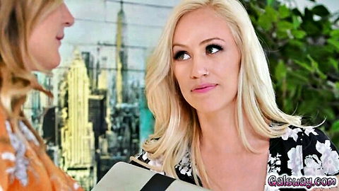 Busty blonde in floral dress with cleavage chats intimately with woman against NYC skyline