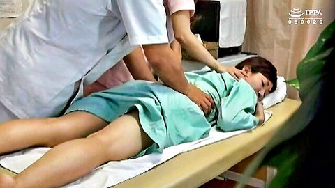 Asian woman in green hospital gown lying on bed, examined intimately by doctor