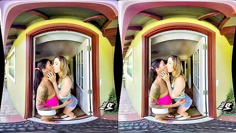 Two tattooed women in bikinis passionately kissing outdoors