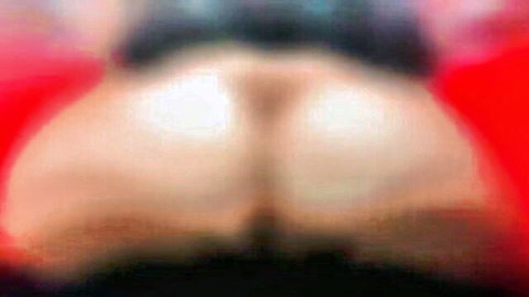 Blurry close-up of pale woman's spread buttocks and anus, red background