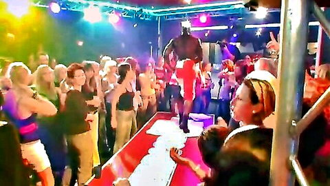 Excited women watching muscular black stripper on stage