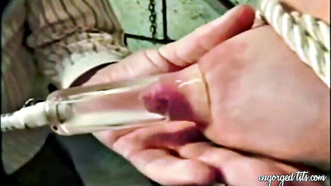 Engorged nipple pumped with vacuum tube in bondage scene